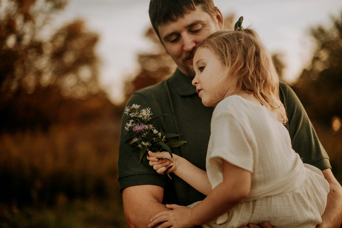 Brookfield, Connecticut: Father holding 4 year old daughter as she clutches a bouquet of wildflowers